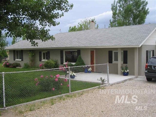 single story home featuring roof with shingles, a fenced front yard, stucco siding, and a front lawn