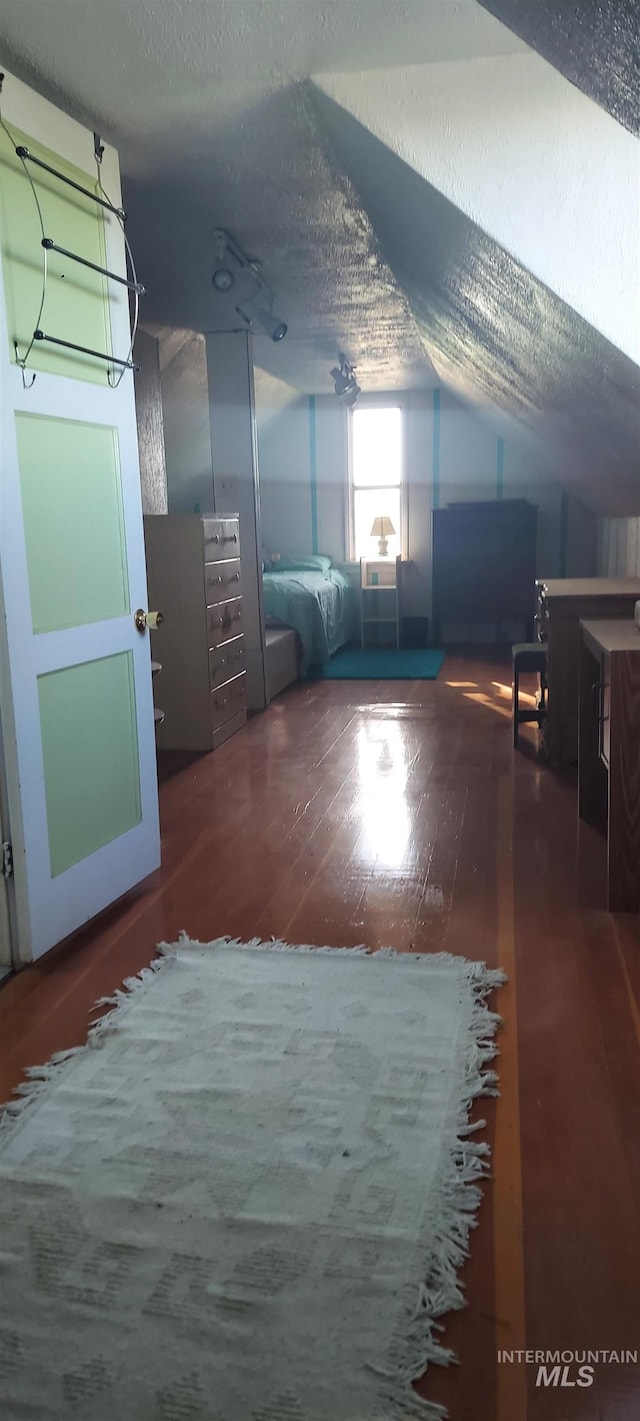 bonus room featuring a textured ceiling, vaulted ceiling, and dark hardwood / wood-style floors