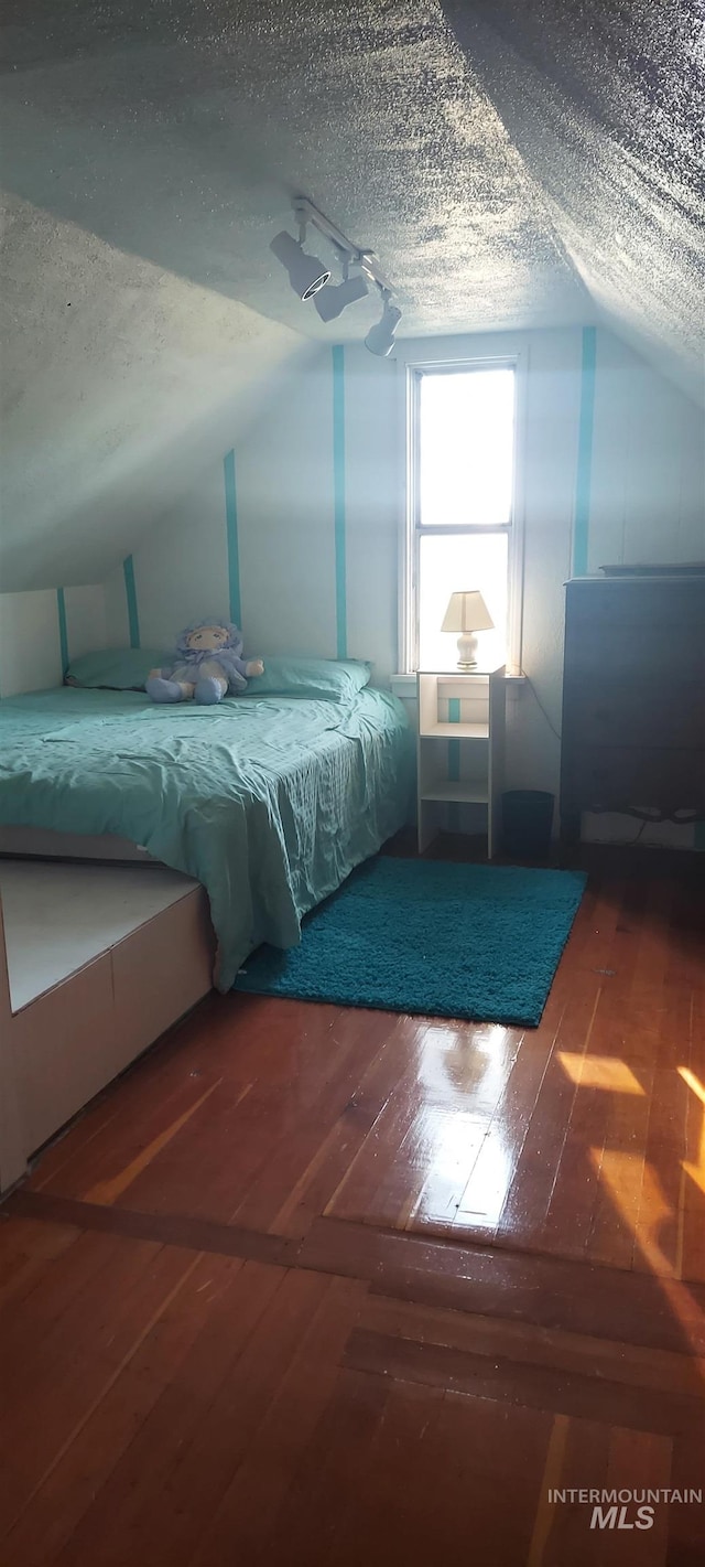 unfurnished bedroom featuring lofted ceiling, a textured ceiling, and hardwood / wood-style flooring