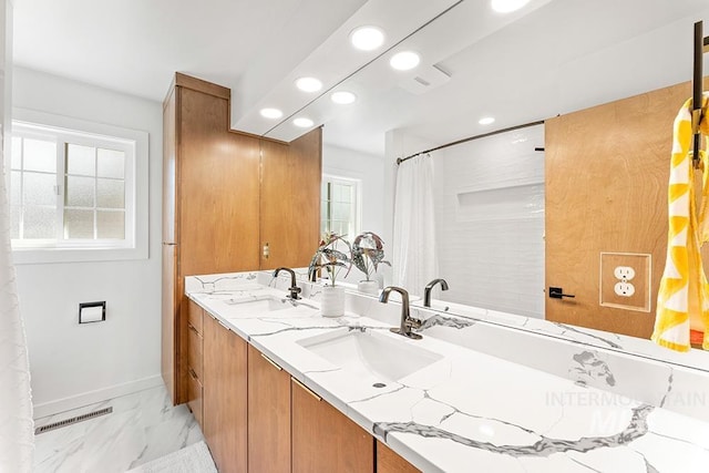 full bath with marble finish floor, plenty of natural light, and a sink