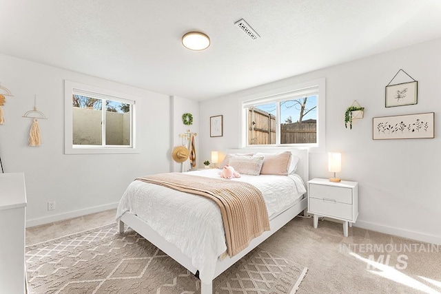 bedroom with baseboards, visible vents, and light colored carpet