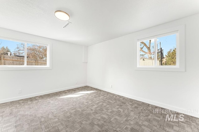 carpeted empty room featuring visible vents and baseboards