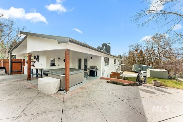 back of house with french doors, a patio, a chimney, a hot tub, and fence