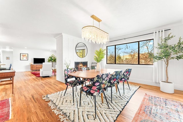 dining area with a chandelier, a brick fireplace, baseboards, and wood finished floors