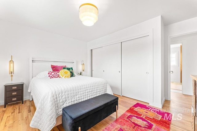 bedroom featuring a closet, light wood-style flooring, and baseboards