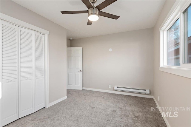 unfurnished bedroom featuring a baseboard heating unit, ceiling fan, a closet, and light carpet