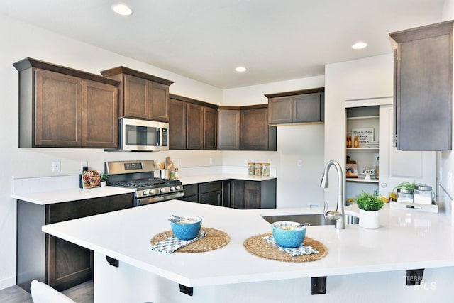 kitchen featuring dark brown cabinets, stainless steel appliances, sink, a breakfast bar, and light hardwood / wood-style floors