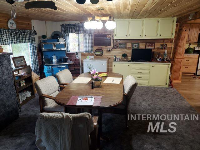3460 American River Rd, Elk City, ID 83525 - dining room featuring a chandelier, wood finished floors, wooden walls, and wooden ceiling