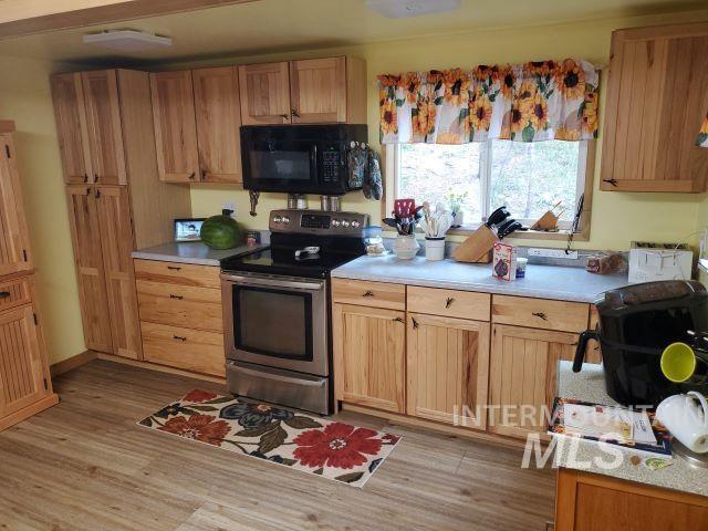 3460 American River Rd, Elk City, ID 83525 - kitchen with black microwave, light countertops, light wood-style floors, and stainless steel electric stove