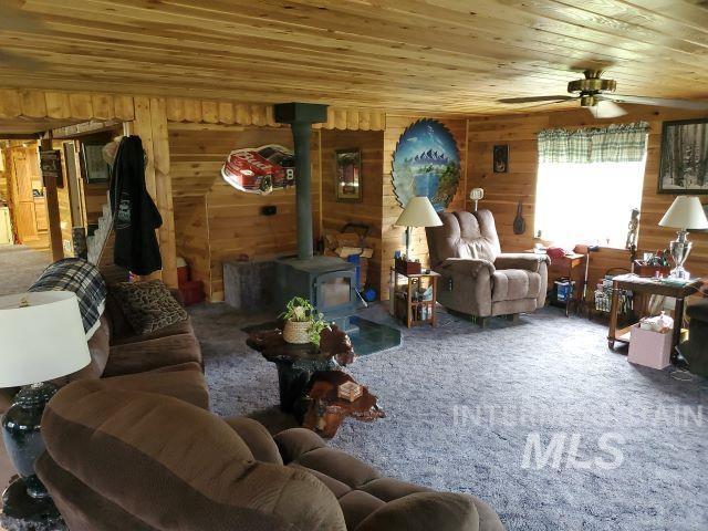 3460 American River Rd, Elk City, ID 83525 - living area with carpet flooring, ceiling fan, wooden ceiling, and a wood stove