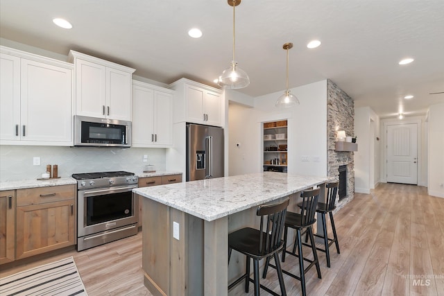 6009 W Riva Capri St, Meridian, ID 83646 - kitchen with light wood finished floors, a center island, a kitchen bar, tasteful backsplash, and appliances with stainless steel finishes