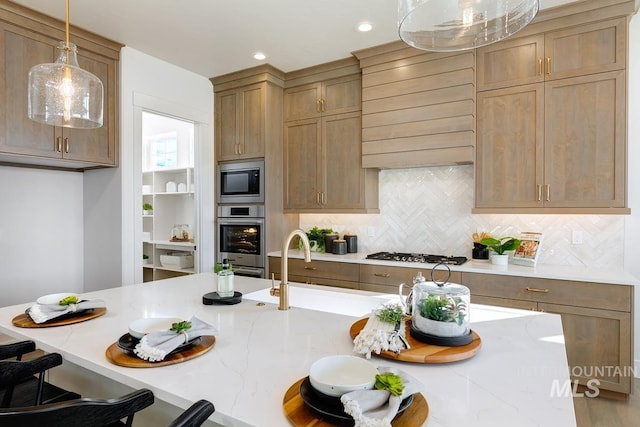 kitchen featuring light stone counters, a breakfast bar area, hanging light fixtures, decorative backsplash, and appliances with stainless steel finishes