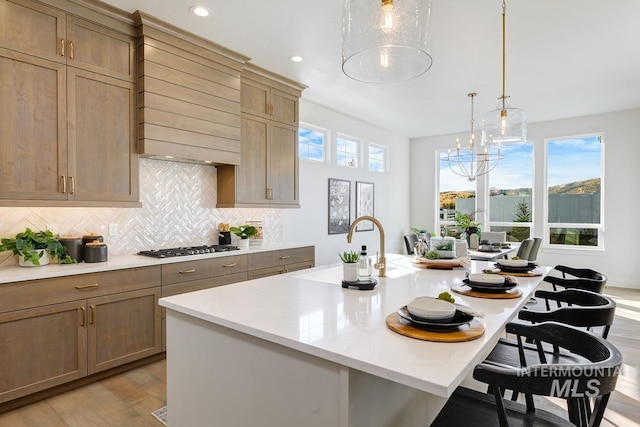 kitchen featuring light wood-type flooring, a breakfast bar, a kitchen island with sink, and plenty of natural light