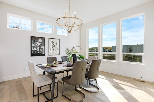 dining room with an inviting chandelier, light wood-type flooring, and a healthy amount of sunlight