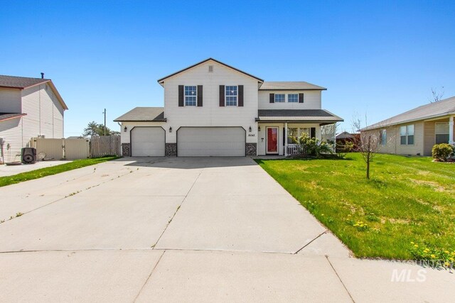 16042 N Saint Helens Dr, Nampa, ID 83651 - traditional home featuring a gate, a front lawn, concrete driveway, an attached garage, and stone siding