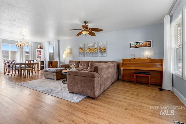 16042 N Saint Helens Dr, Nampa, ID 83651 - living room featuring light wood-style floors, visible vents, and ceiling fan with notable chandelier