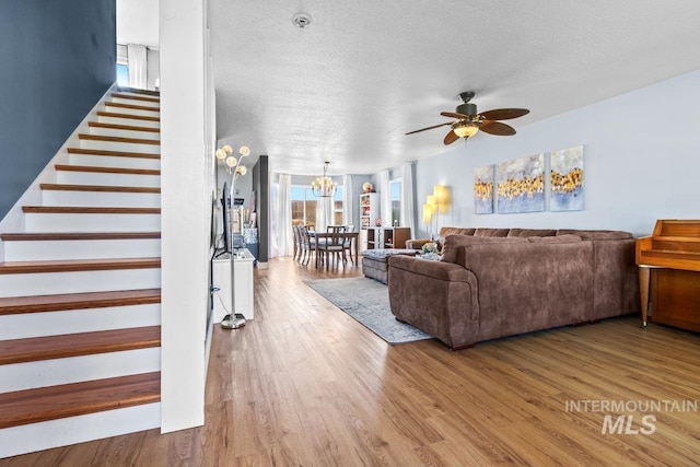 16042 N Saint Helens Dr, Nampa, ID 83651 - living room with wood finished floors, a textured ceiling, stairs, and ceiling fan with notable chandelier