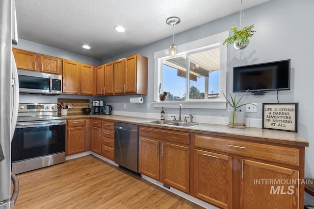 16042 N Saint Helens Dr, Nampa, ID 83651 - kitchen with brown cabinets, light wood-style flooring, appliances with stainless steel finishes, and a sink