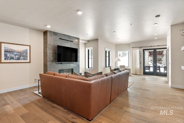 living room featuring french doors, a tiled fireplace, and light hardwood / wood-style flooring