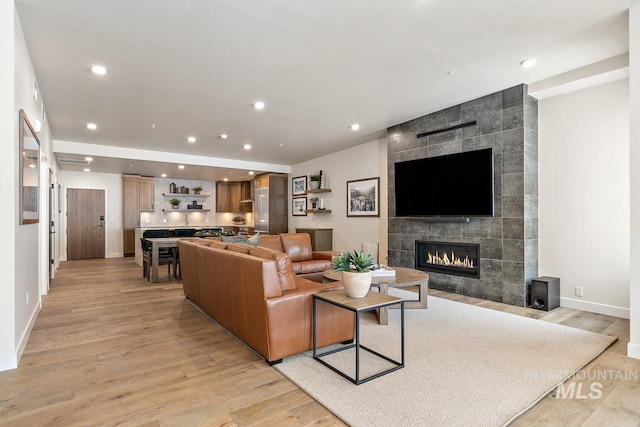 living room with a tile fireplace and light hardwood / wood-style flooring