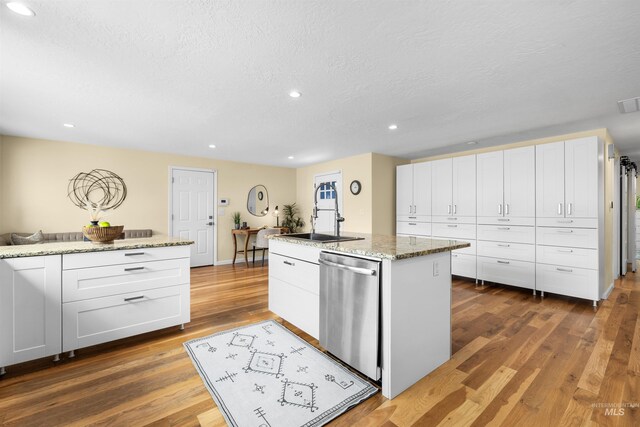 kitchen featuring a textured ceiling, dishwasher, and white cabinetry