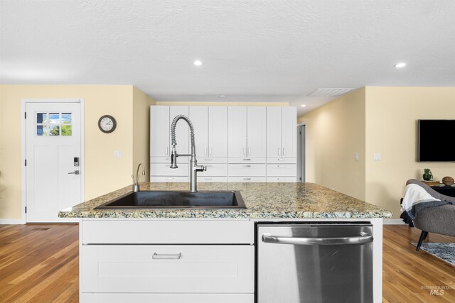 kitchen with a sink, baseboards, light wood finished floors, and dishwasher