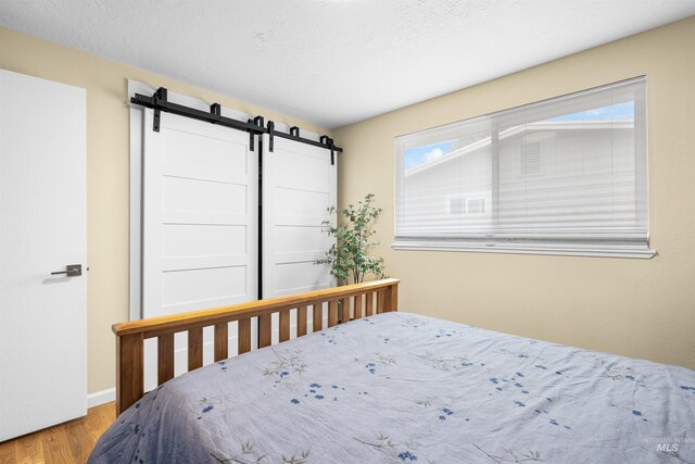 bedroom featuring a barn door and wood finished floors