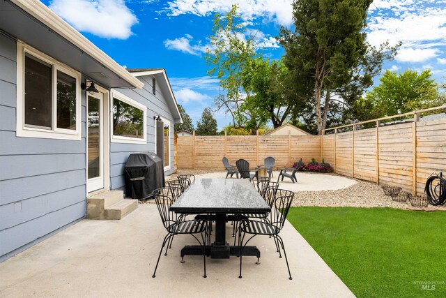 view of patio with grilling area, outdoor dining area, a fenced backyard, and entry steps