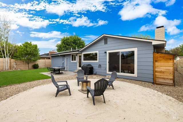 back of property with a fenced backyard, outdoor dining area, a chimney, a patio, and a yard