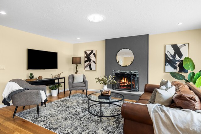 living area featuring recessed lighting, baseboards, a large fireplace, and wood finished floors