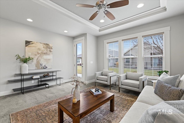 carpeted living room featuring ceiling fan and a raised ceiling