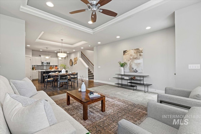 living room with dark hardwood / wood-style flooring, a tray ceiling, and ceiling fan