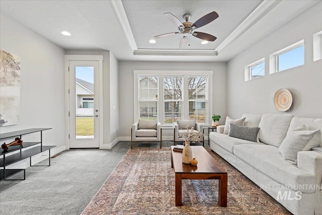 carpeted living room featuring ceiling fan and a raised ceiling