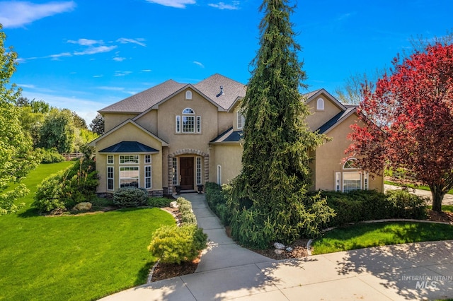 traditional home with a front lawn, stucco siding, and stone siding