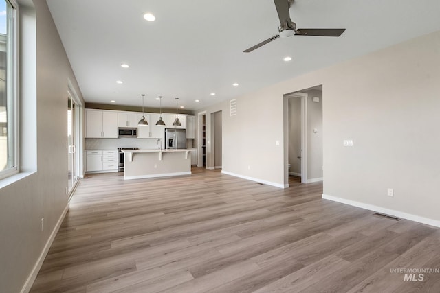 unfurnished living room with recessed lighting, baseboards, and light wood-style flooring