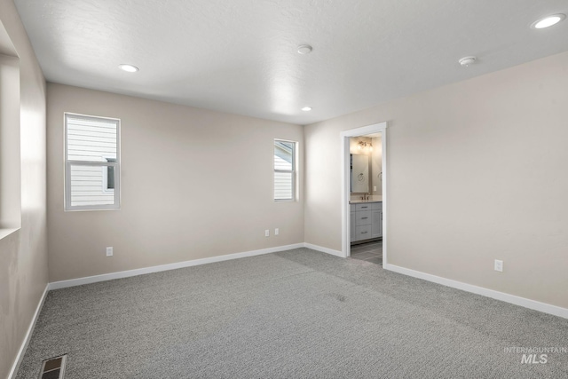 unfurnished bedroom with carpet, visible vents, baseboards, recessed lighting, and ensuite bathroom