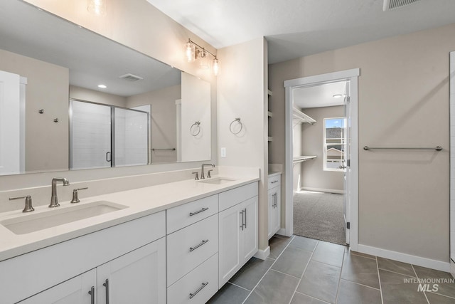 full bath featuring a sink, a stall shower, double vanity, and tile patterned floors