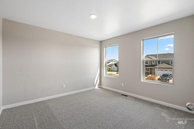 carpeted empty room featuring baseboards