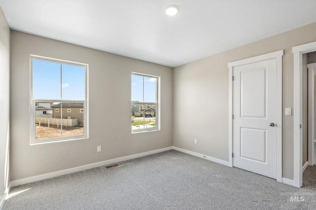 carpeted spare room featuring visible vents and baseboards