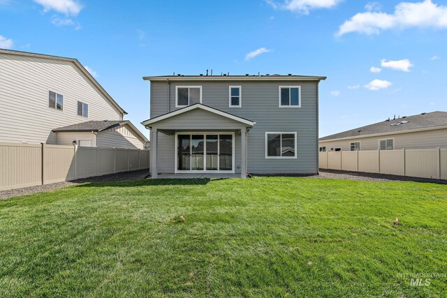 rear view of property featuring a lawn and a fenced backyard