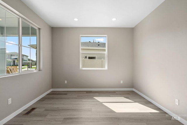 spare room featuring light wood-style flooring, baseboards, and visible vents