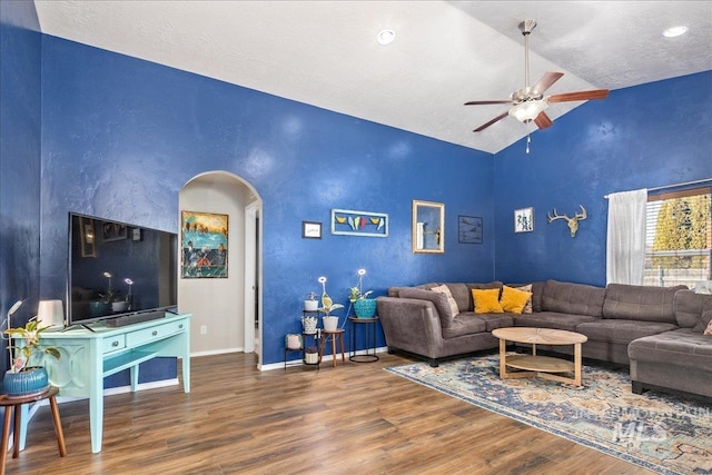 living area with arched walkways, ceiling fan, a textured ceiling, wood finished floors, and baseboards