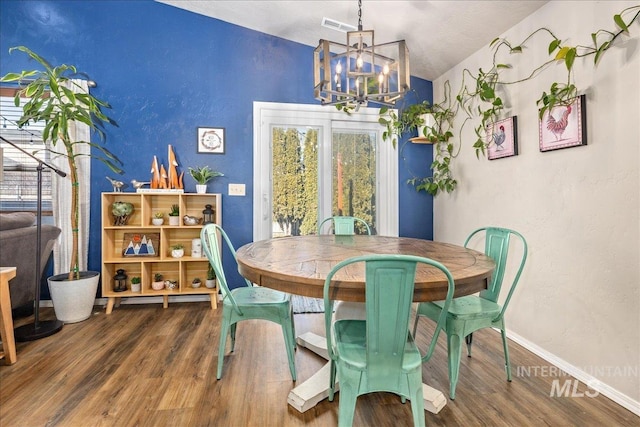 dining space featuring visible vents, vaulted ceiling, wood finished floors, a chandelier, and baseboards