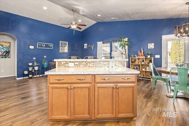 kitchen featuring arched walkways, ceiling fan, lofted ceiling, light countertops, and dark wood-style floors