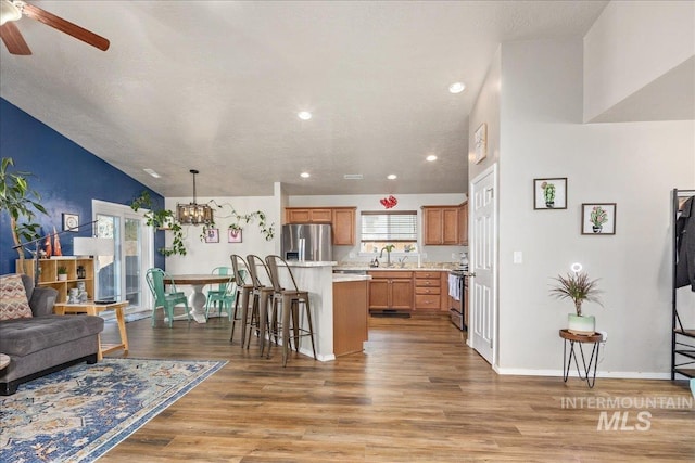 kitchen featuring a breakfast bar, light countertops, appliances with stainless steel finishes, open floor plan, and light wood-type flooring