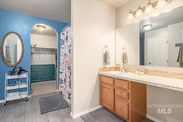 full bathroom with baseboards, a textured ceiling, and vanity