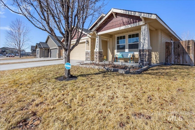 craftsman house with a porch, concrete driveway, an attached garage, fence, and a front lawn