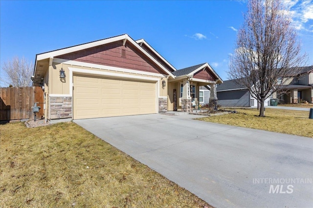 craftsman-style house featuring an attached garage, a front yard, fence, stone siding, and driveway