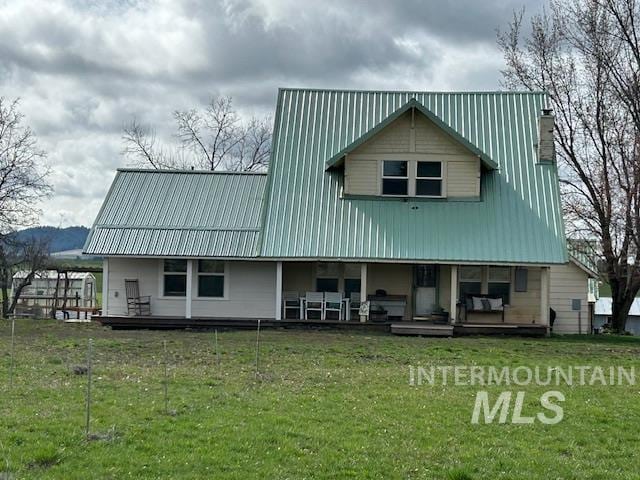 rear view of house with a lawn, a porch, and metal roof