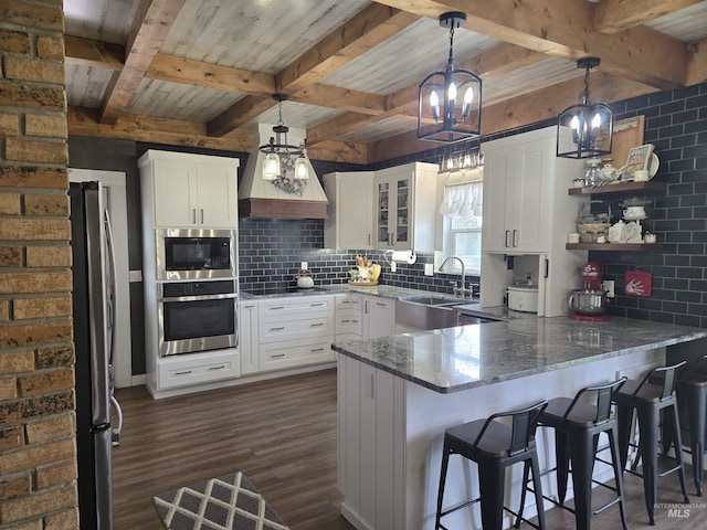 kitchen with stainless steel appliances, a peninsula, dark wood-style floors, a sink, and tasteful backsplash